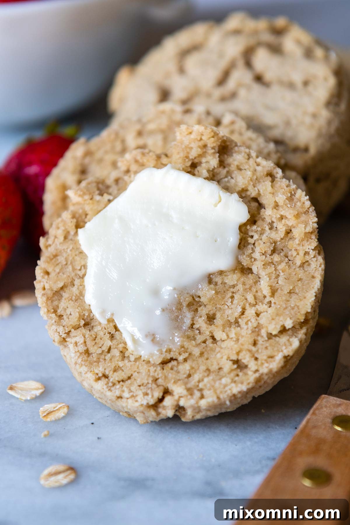 A tender oat flour biscuit sliced in half, with a generous pat of butter slowly melting into its fluffy interior.