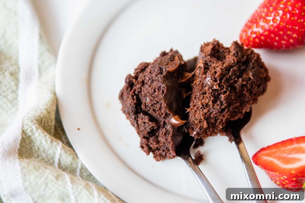 Two spoons of brownies side-by-side on a white plate; the left spoon holds a fudgy brownie, and the right spoon holds a cakier, lighter brownie.