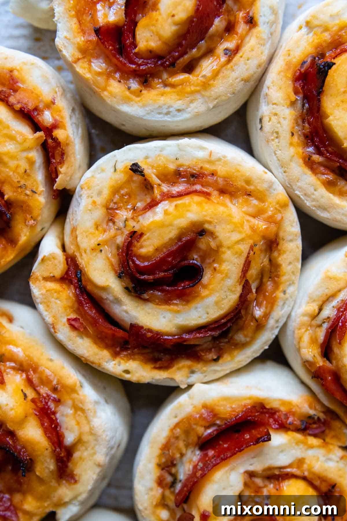 Overhead shot of freshly baked, golden-brown gluten-free pizza rolls, neatly arranged and glistening with melted cheese, ready to be served.