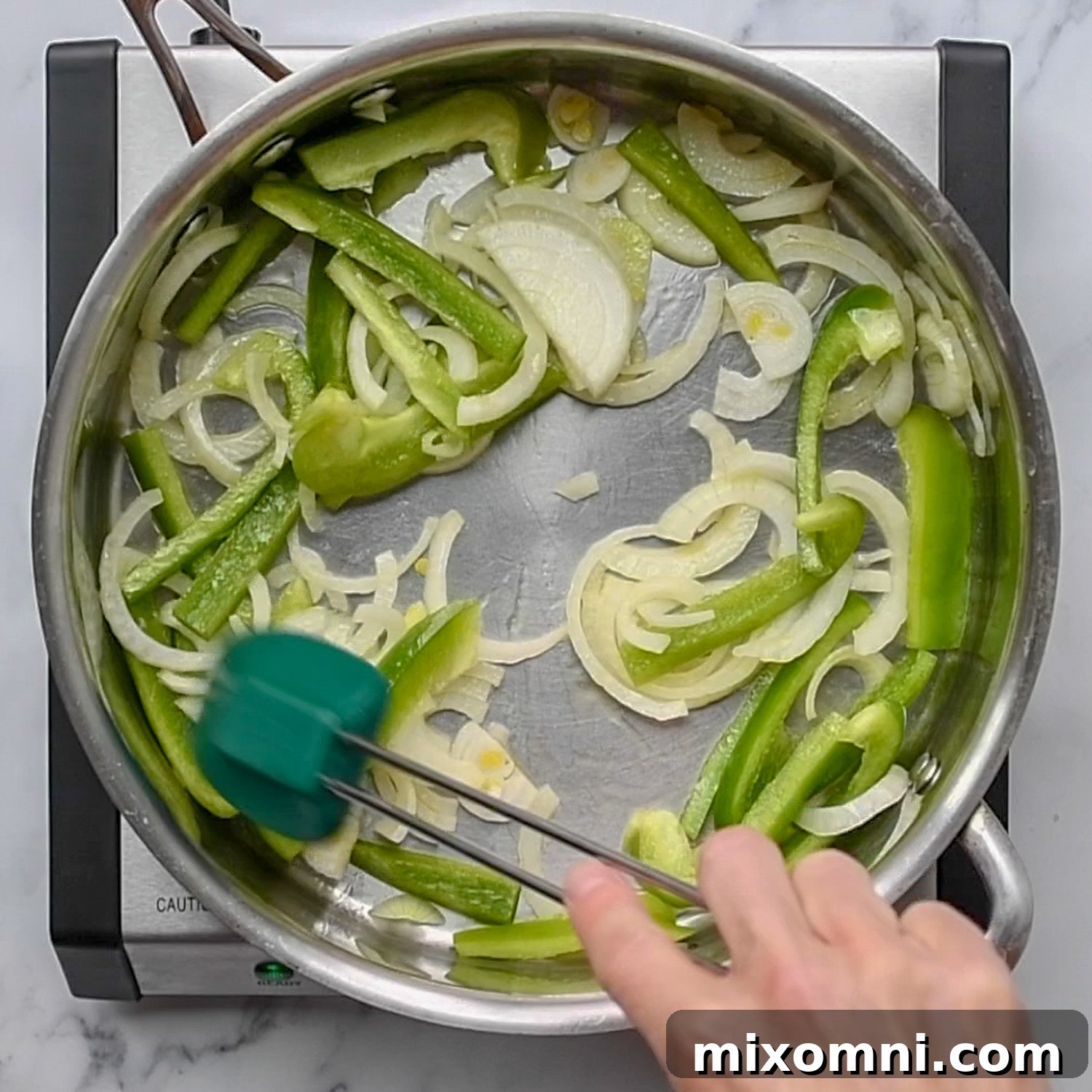 Bell peppers and onions sautéing in a skillet.