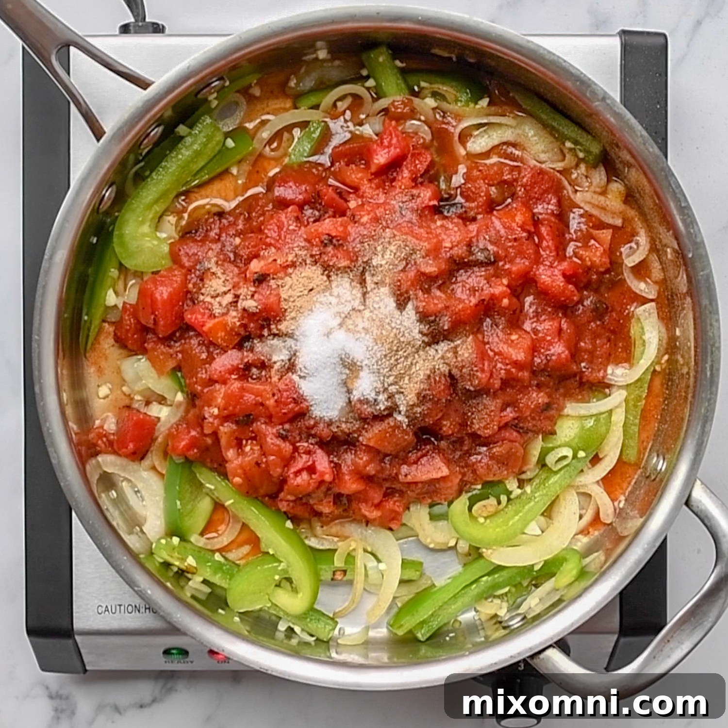 Salsa and seasonings added to sautéed peppers and onions in a skillet.