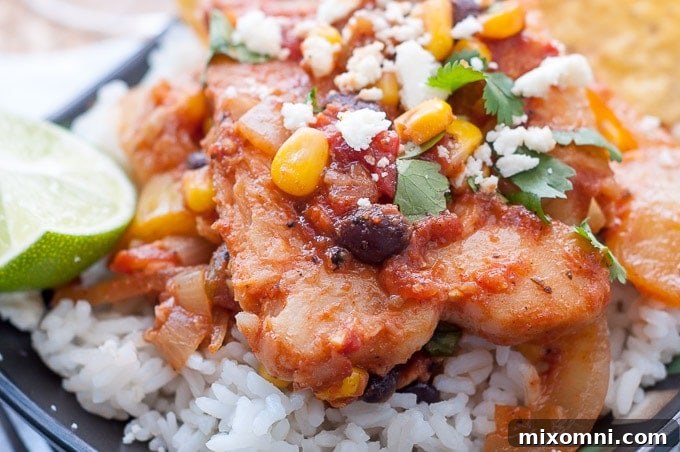 Close-up of Mexican fish recipe served on a bed of rice on a black plate.