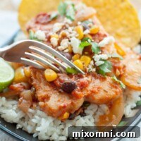 A fork about to cut into a plate of Mexican fish served on rice.