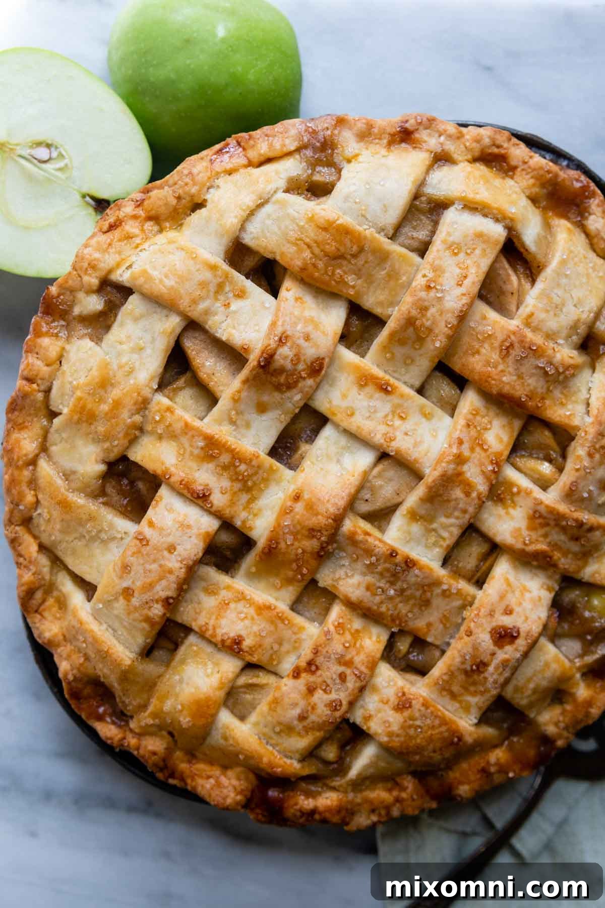 An overhead shot of a freshly baked gluten-free apple pie, with sliced apples arranged artfully beside it.