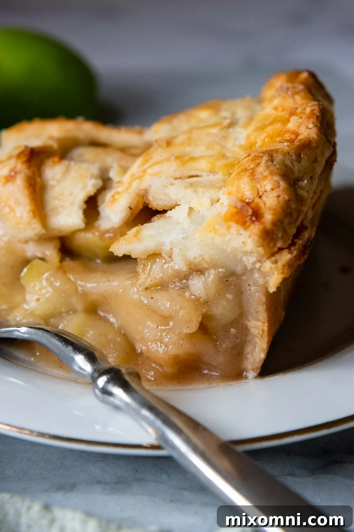 A close-up of a slice of gluten-free apple pie with a fork resting beside it, highlighting the flaky crust.