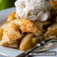 A slice of homemade gluten-free apple pie on a white plate with ice cream on top.