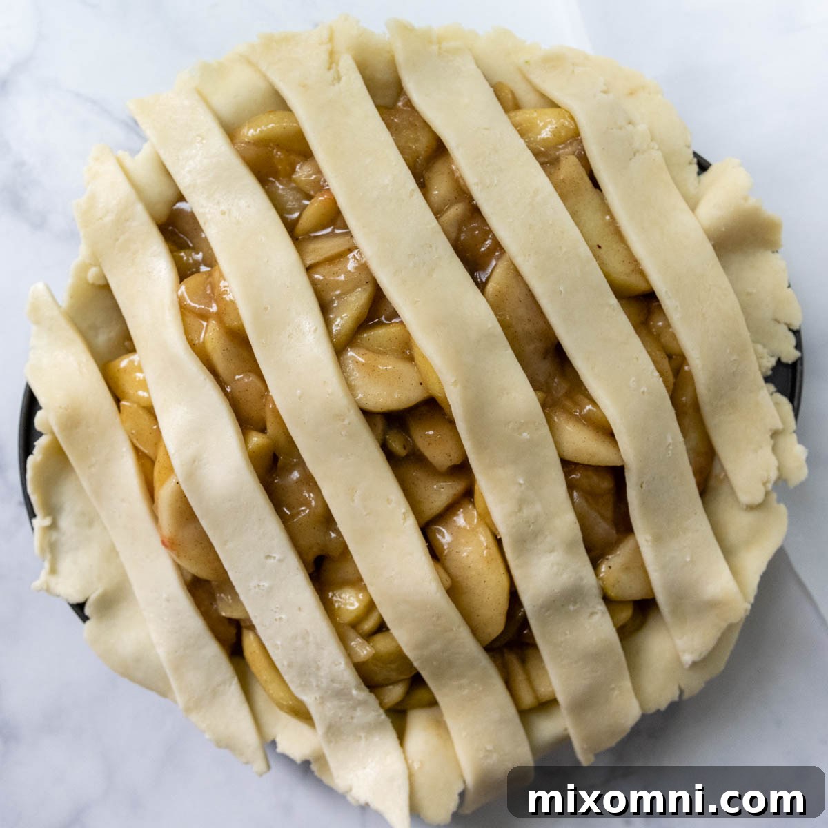 The initial stage of a lattice crust, with six strips laid parallel across the apple filling.