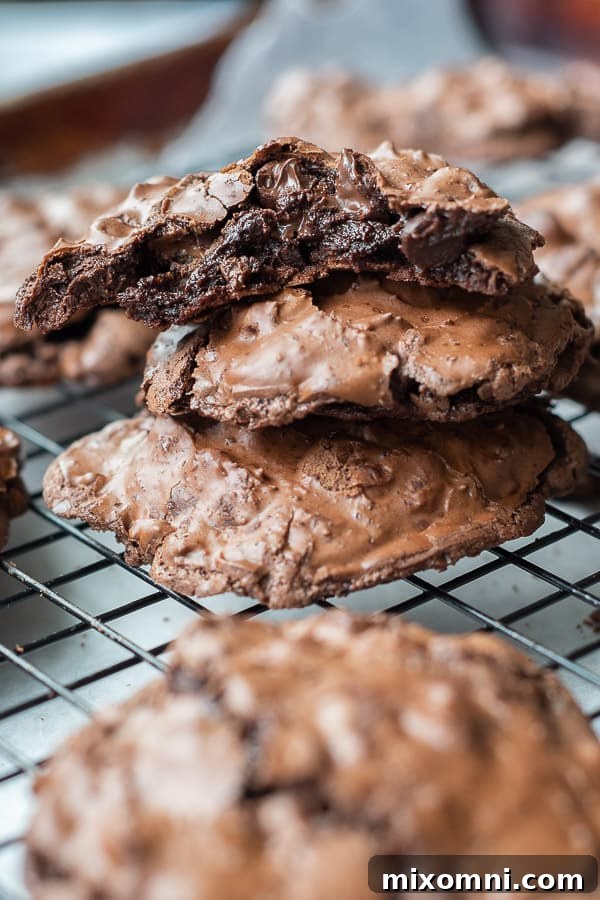 A fresh stack of chewy, fudgy flourless chocolate cookies cooling on a wire rack.