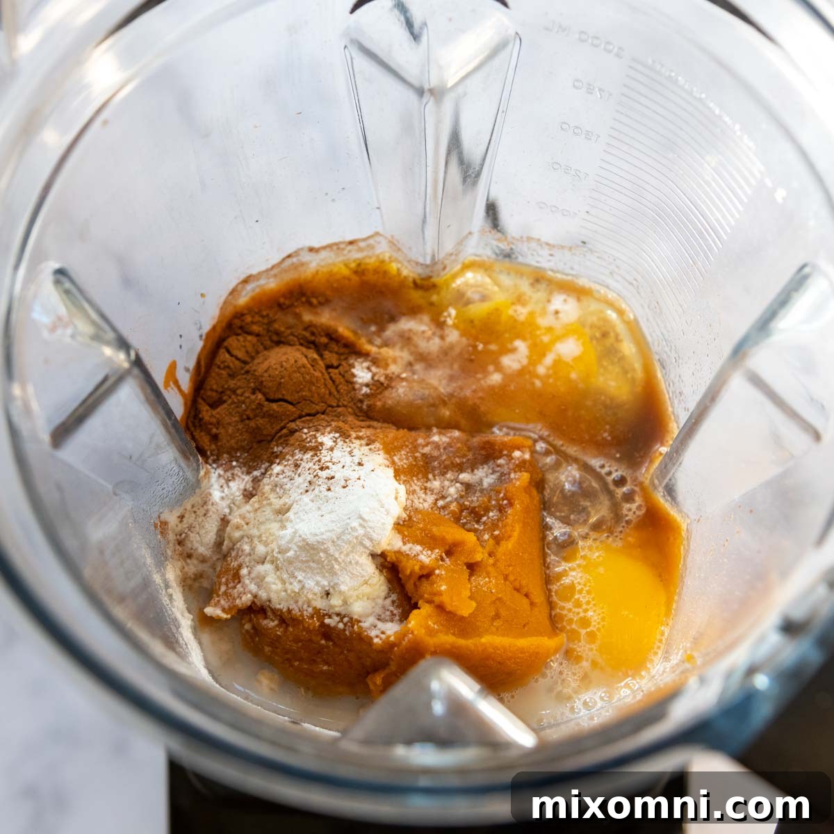 All the pumpkin pancake ingredients, including oats, pumpkin puree, eggs, and milk, placed in a high-speed blender, ready for blending.