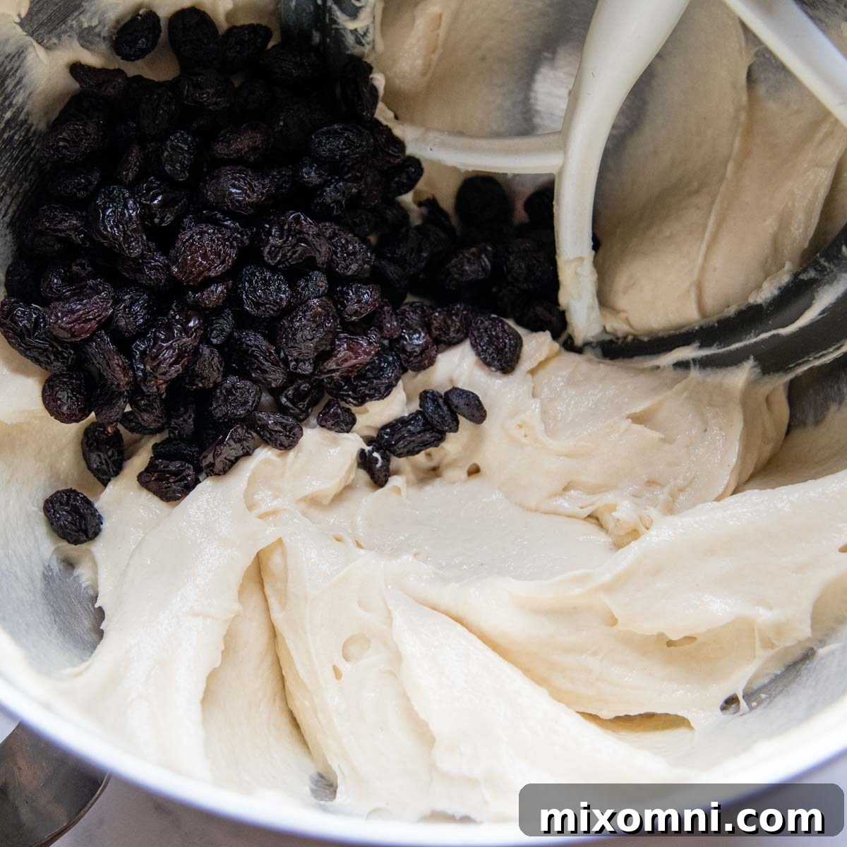 A large mixing bowl contains the soft gluten-free bread dough, with raisins visibly stirred in.