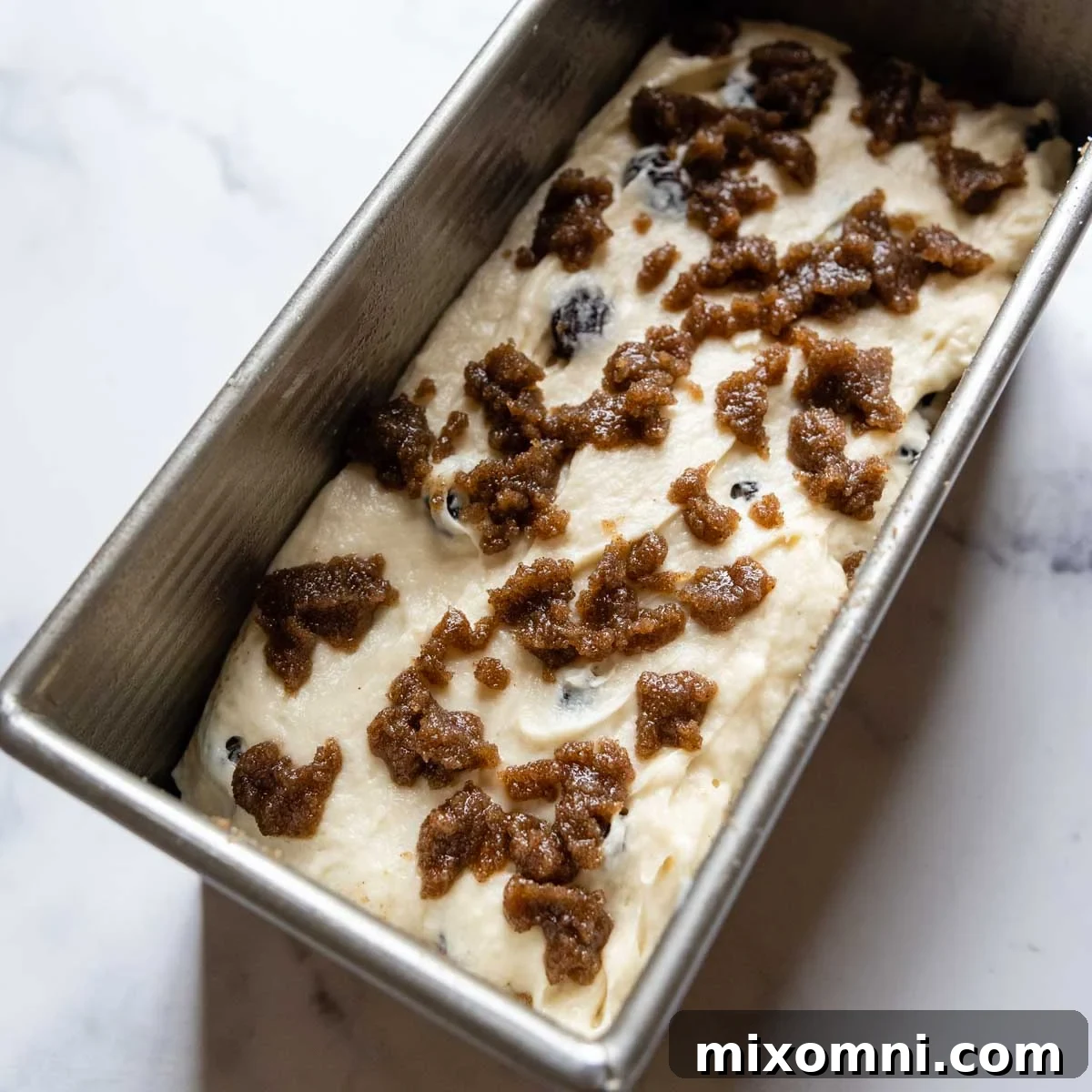 The remaining dough is dolloped on top of the first layer, and the butter-infused cinnamon mixture is spread over it before swirling.