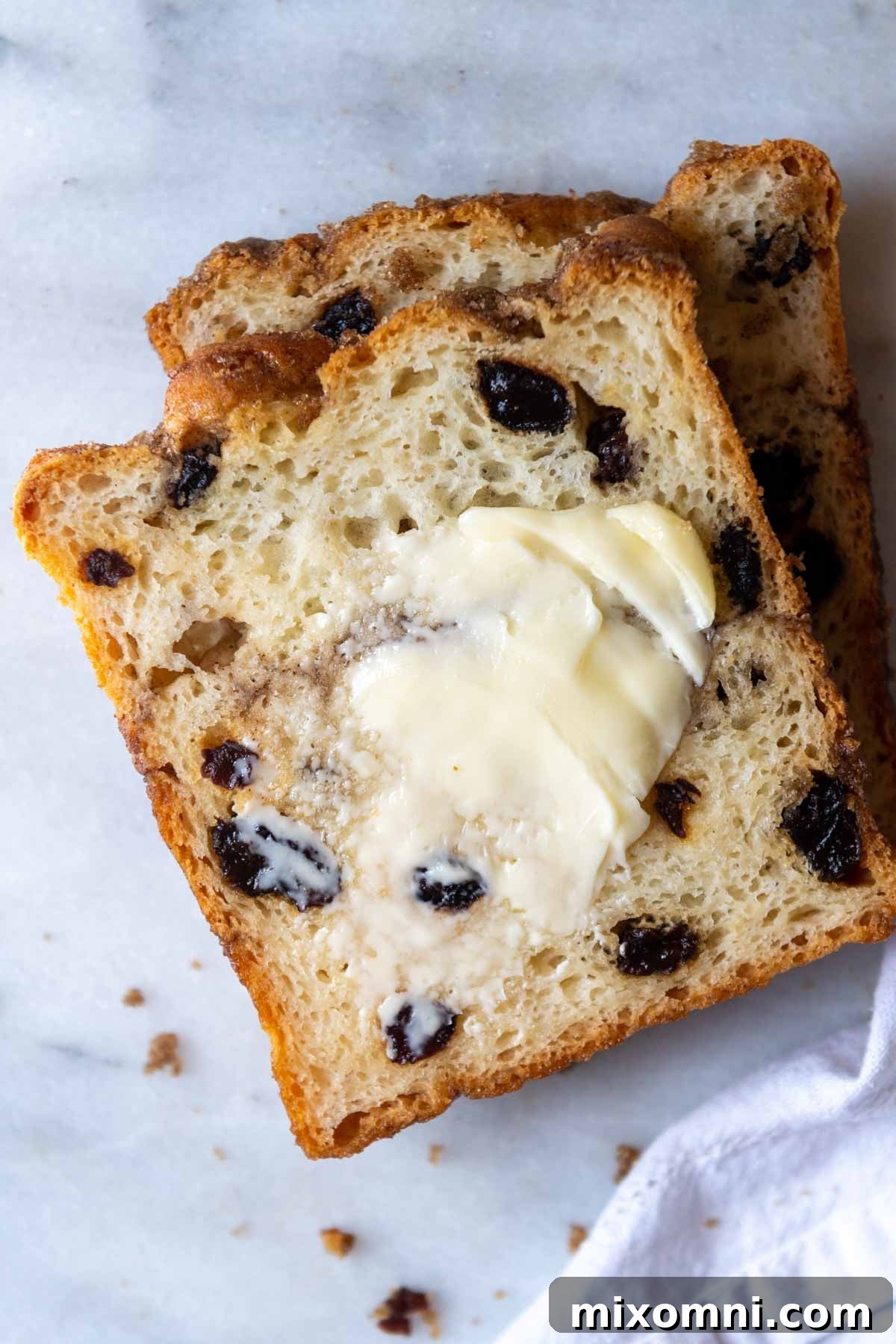 A slice of gluten-free cinnamon raisin bread with butter generously spread on top, ready to be enjoyed.