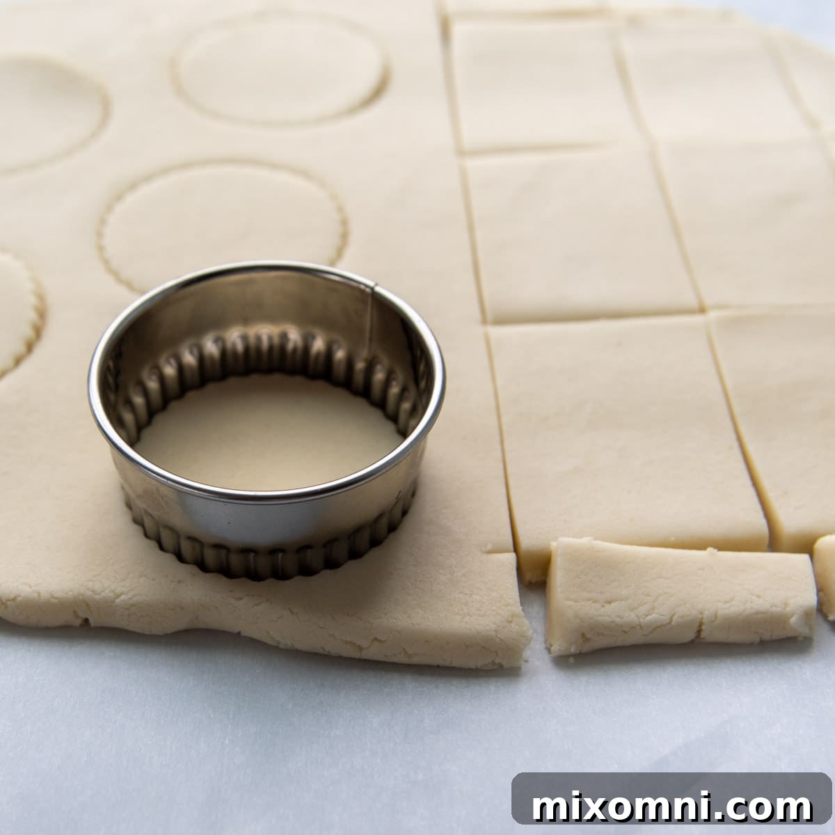 A biscuit cutter pressing into rolled out gluten-free shortbread dough, creating perfect shapes for baking.