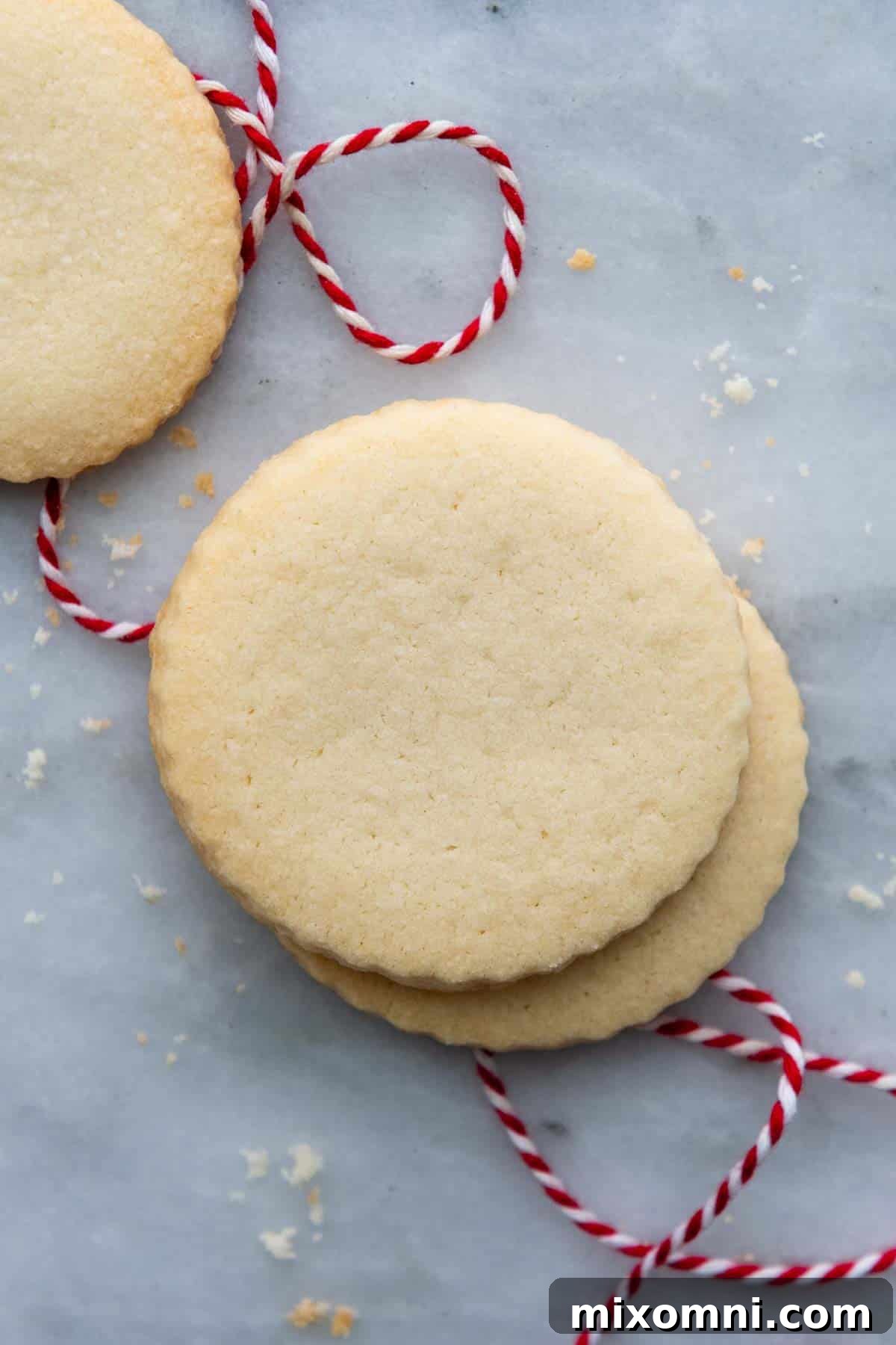 Two beautifully baked gluten-free shortbread cookies stacked with a decorative red thread tied underneath, highlighting their golden hue.