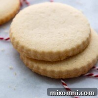 Side view of two stacked gluten-free shortbread cookies on a marble surface, beautifully golden.