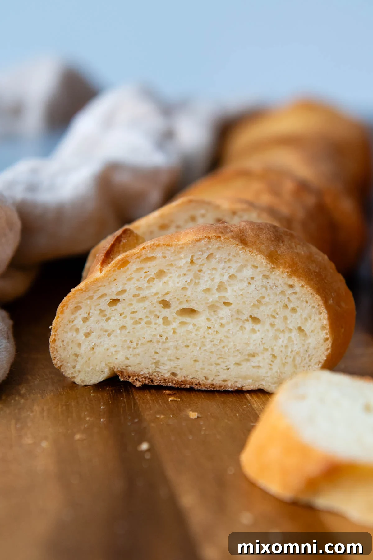 A freshly baked, golden-brown gluten-free French bread baguette resting on a rustic wooden cutting board, ready to be sliced and enjoyed.