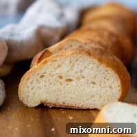 A perfectly baked gluten-free French bread baguette on a wooden cutting board, ready to be sliced and served.