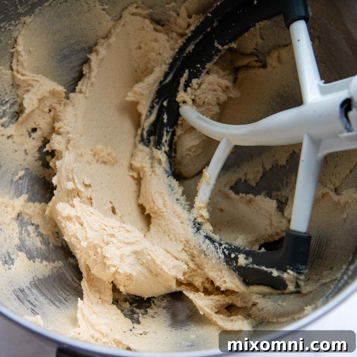 Creamed butter and sugars in a mixing bowl, light and fluffy, ready for eggs.