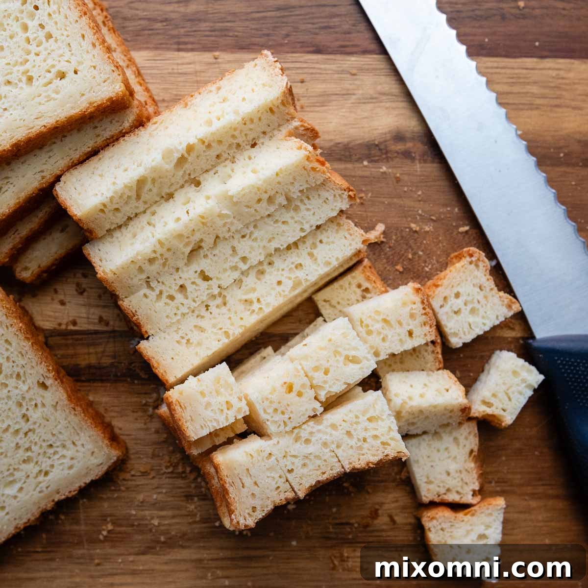 gluten-free bread cubed on a wooden cutting board, ready for the casserole.
