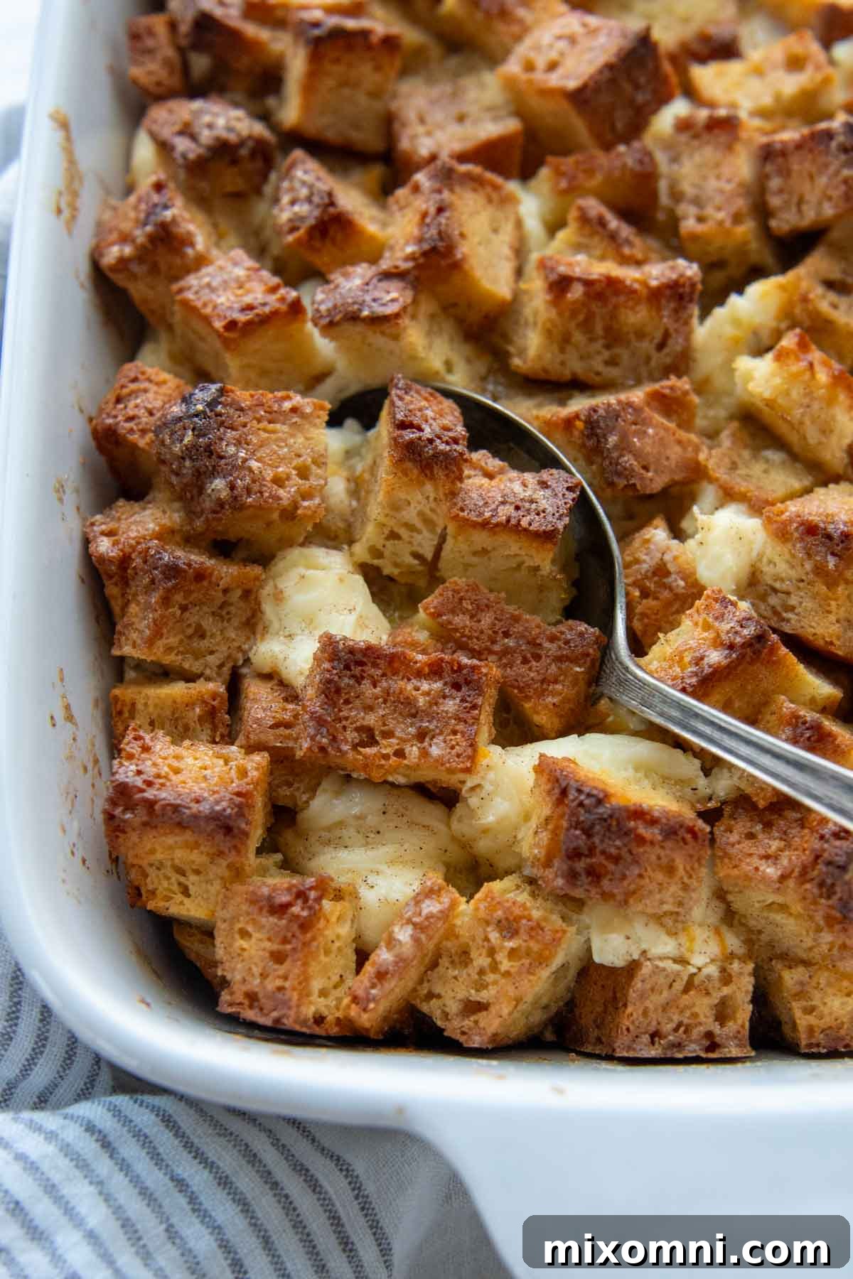 a spoon going into the top of the gluten-free french toast casserole, showing the crisp crust and soft interior.