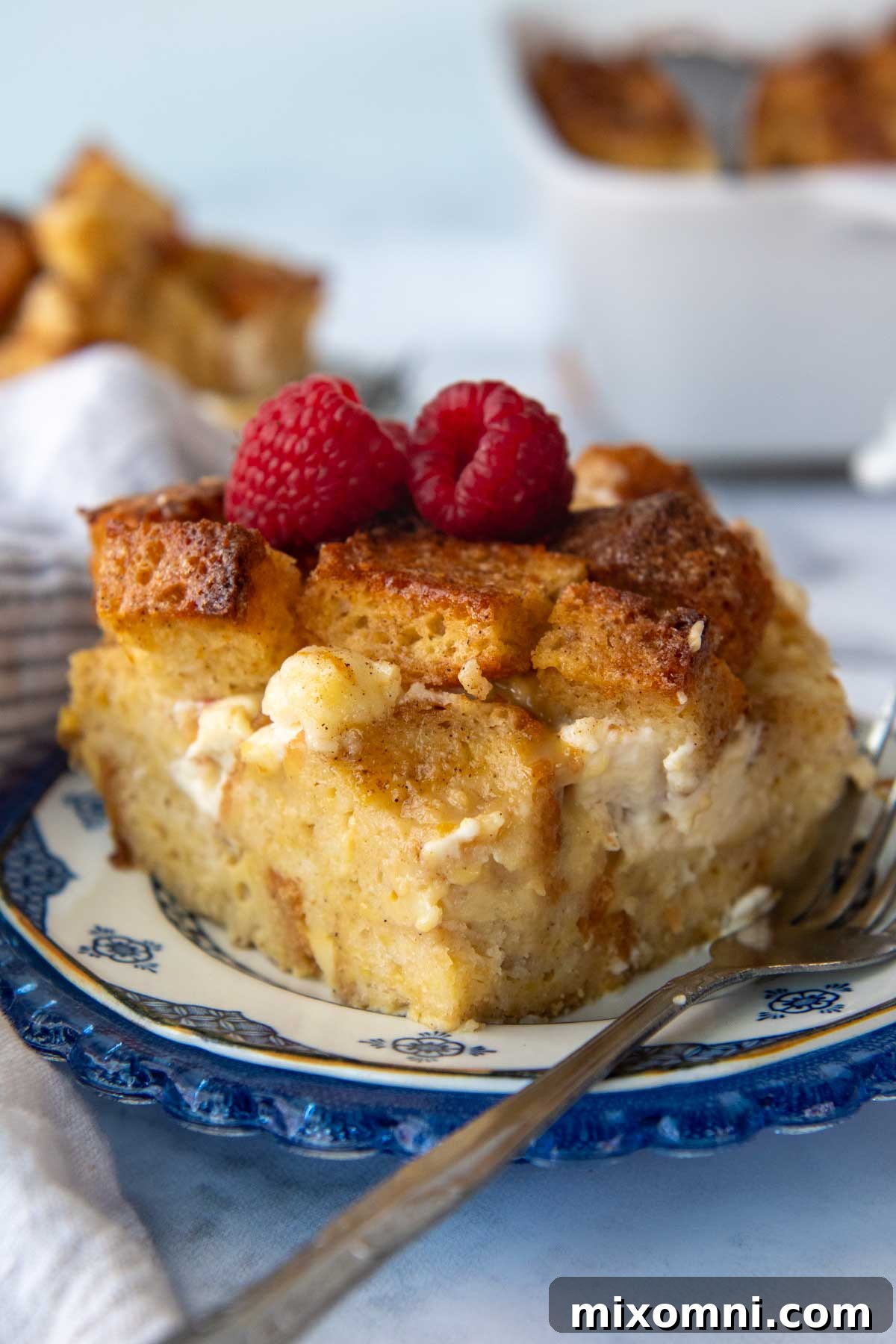 a slice of gluten-free french toast bake on a blue plate with fresh berries on top, ready to be served.
