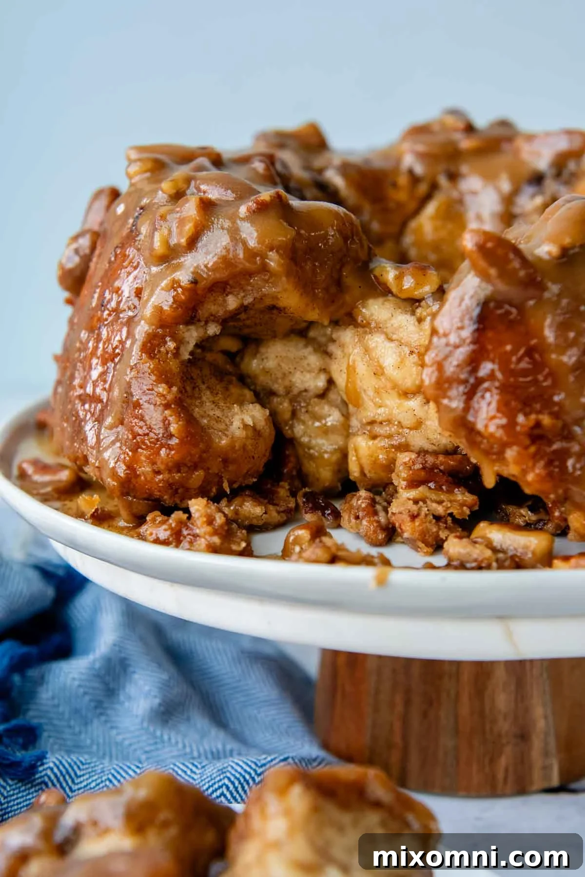 Gluten-free monkey bread on a cake platter, with some pieces pulled apart, showcasing its gooey texture.