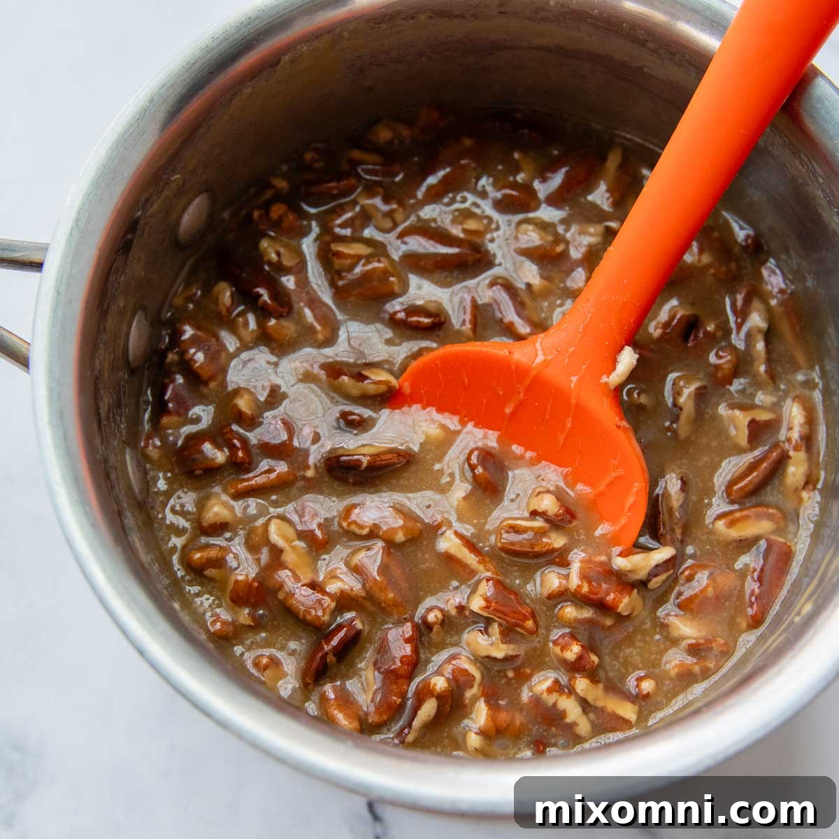 The finished sticky caramel sauce with chopped pecans, ready to be poured.