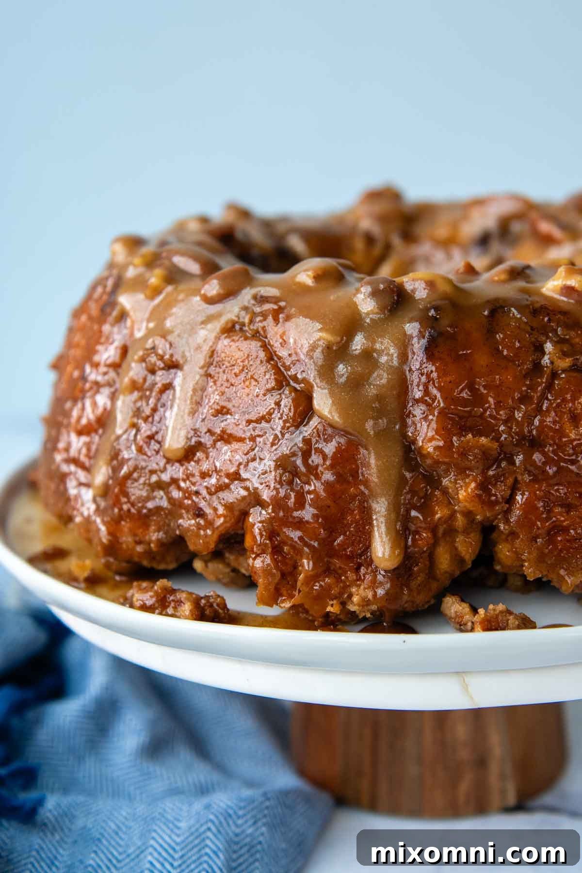 A beautifully baked gluten-free cinnamon pull-apart bread on a cake platter, showcasing its golden-brown crust and sticky glaze.