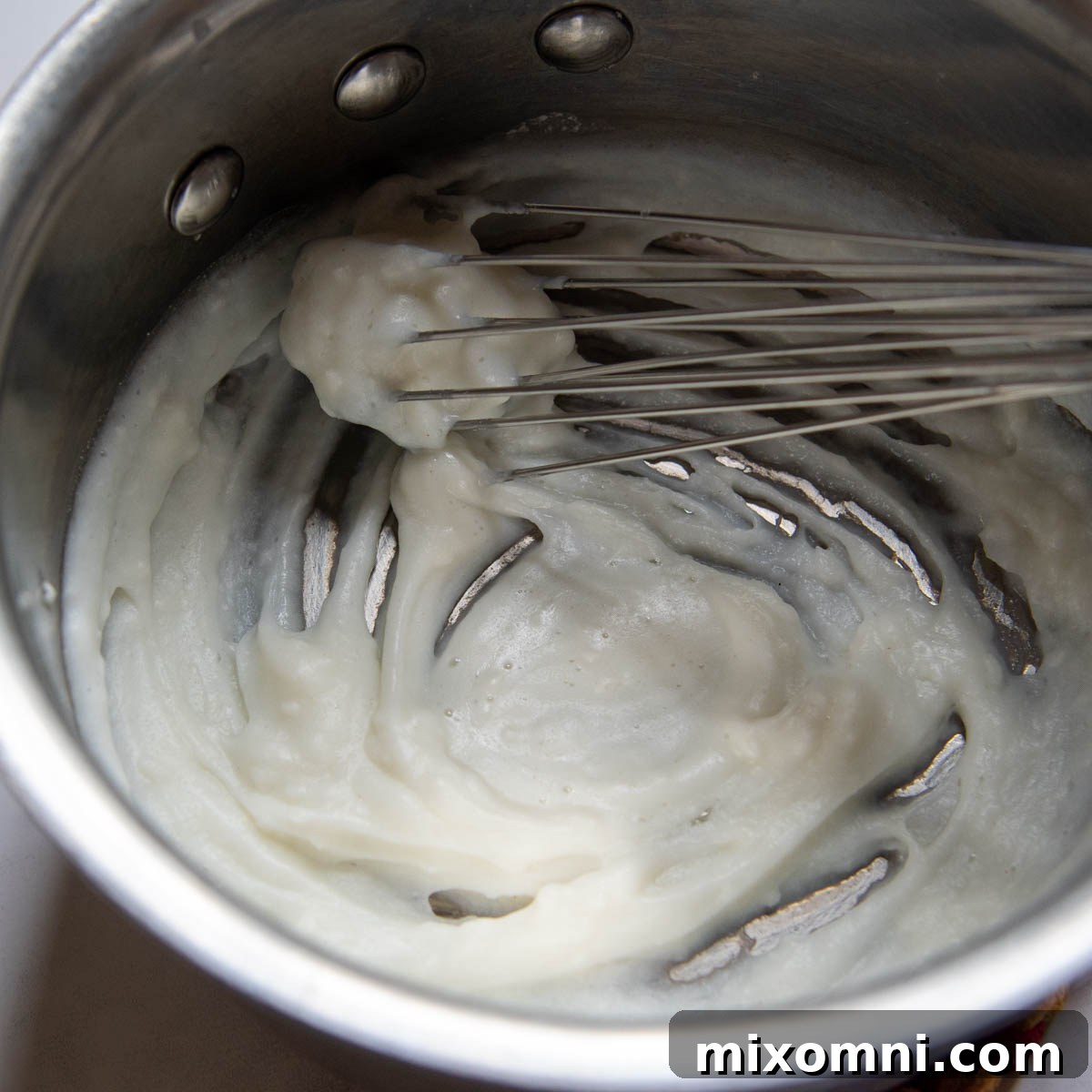 The roux thickening in a saucepan, showing the trail separation at the bottom.