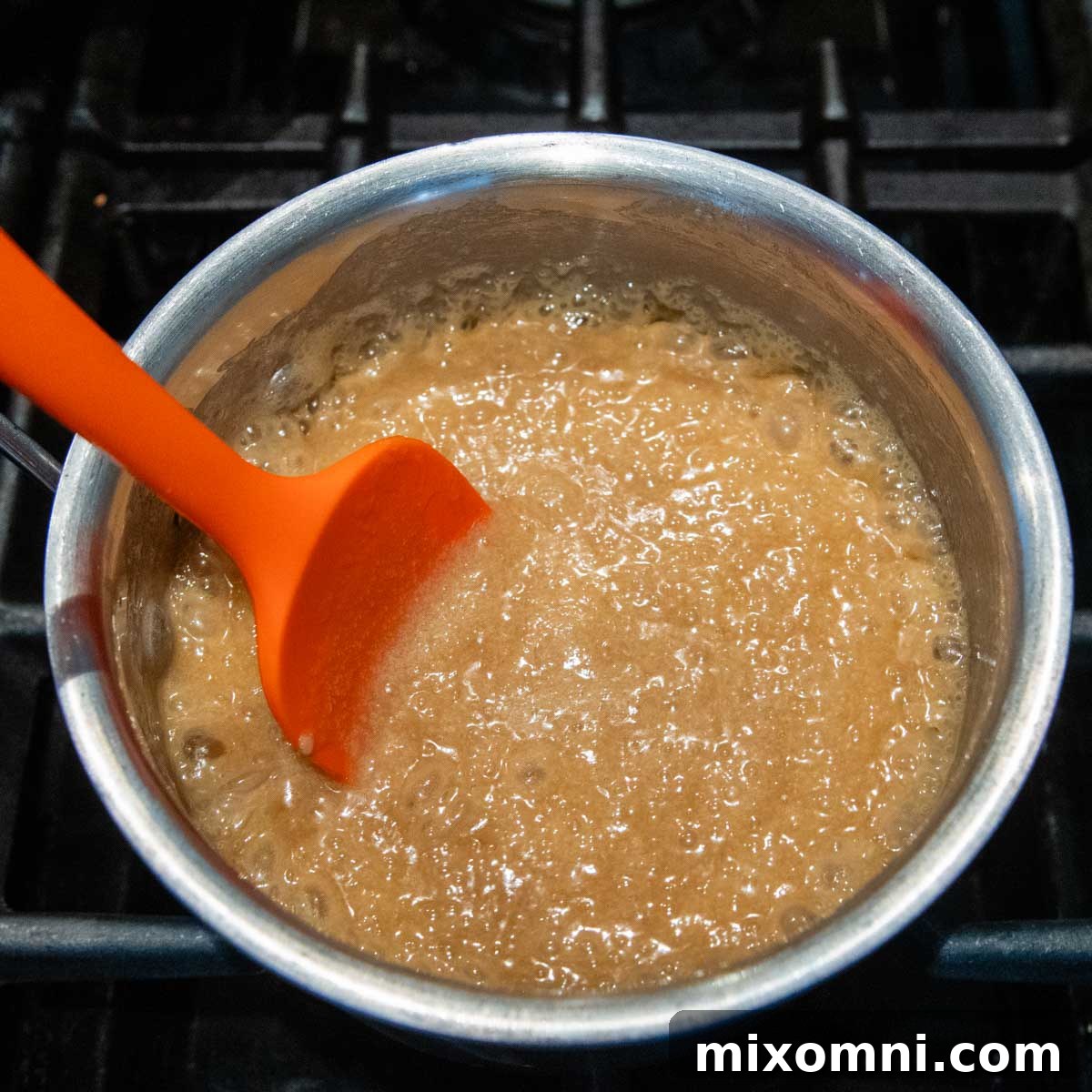 Caramel sauce boiling vigorously in a saucepan on the stove.