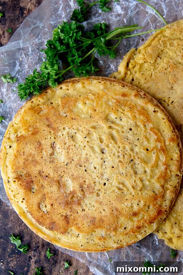 An overhead shot of a round, golden-brown socca flatbread, perfectly cooked and garnished with fresh parsley sprigs laid next to it on a rustic wooden surface, highlighting its natural appeal.