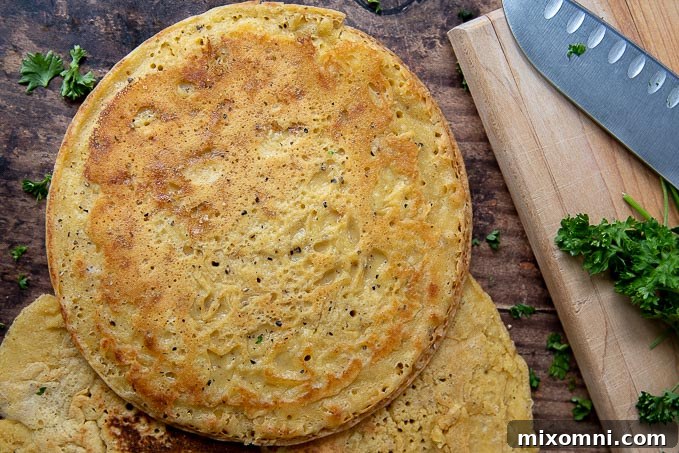 An uncut, perfectly golden-brown farinata flatbread resting gracefully beside a small wooden cutting board, with scattered chopped fresh parsley nearby, waiting to be garnished and served.
