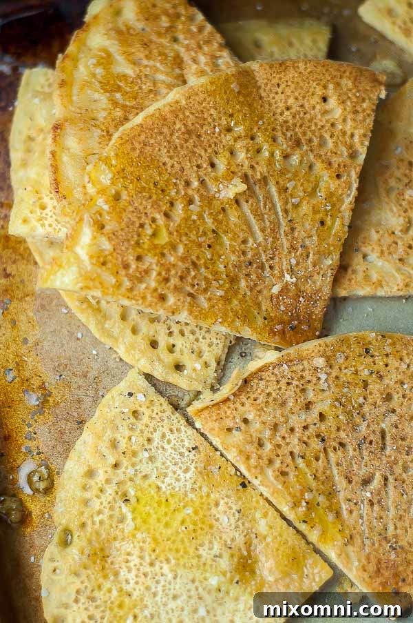 An overhead shot of golden-brown socca flatbread, expertly cut into inviting wedges and lightly drizzled with glistening olive oil, ready for serving.