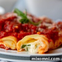 close up of the inside of manicotti on a white plate.