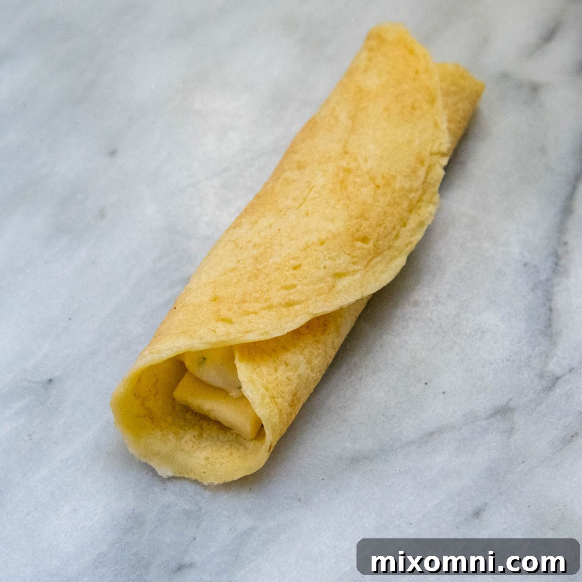 A gluten-free manicotti shell, perfectly rolled up with its filling enclosed, ready for baking.