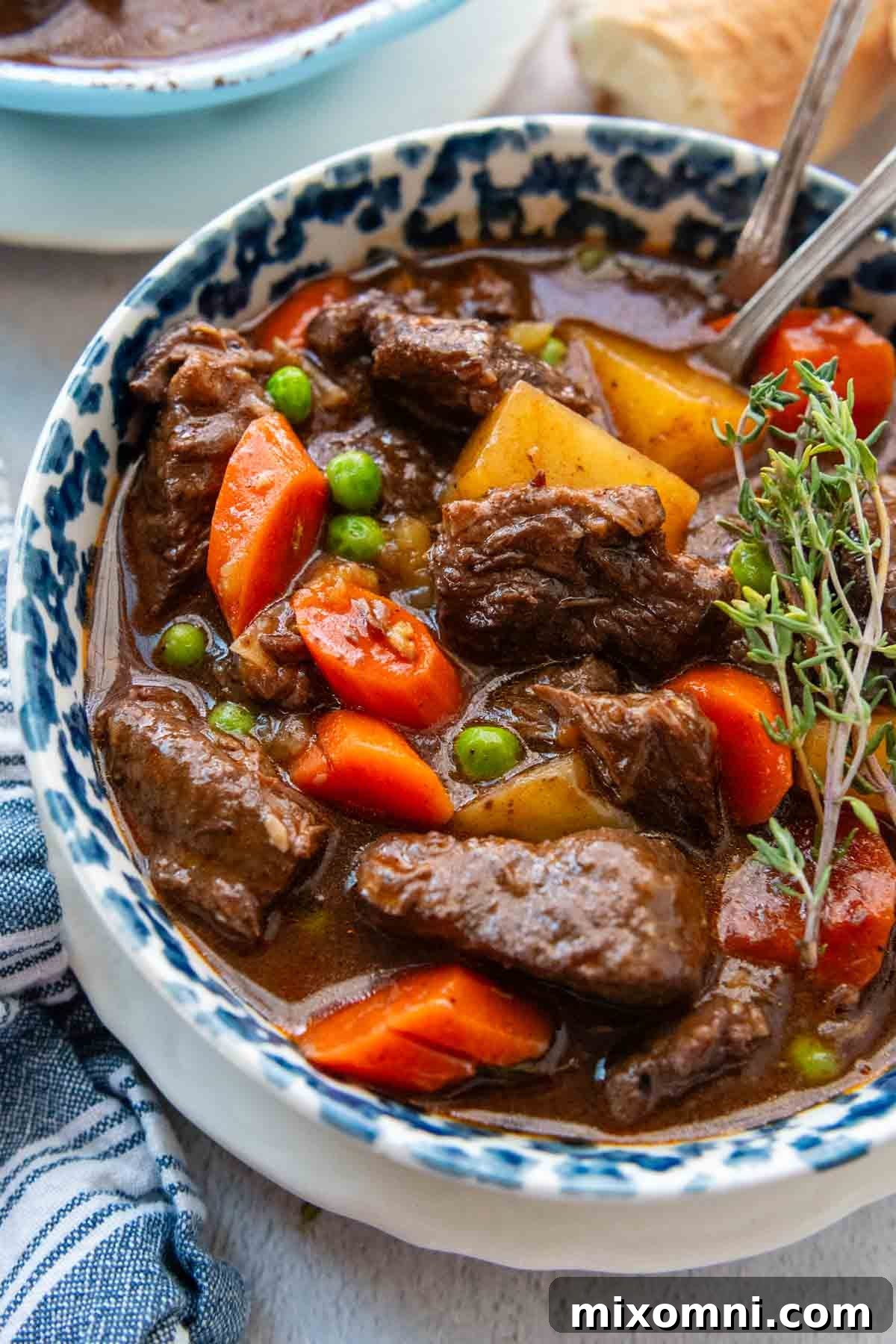 overhead shot of a bowl of beef stew with a blue napkin.