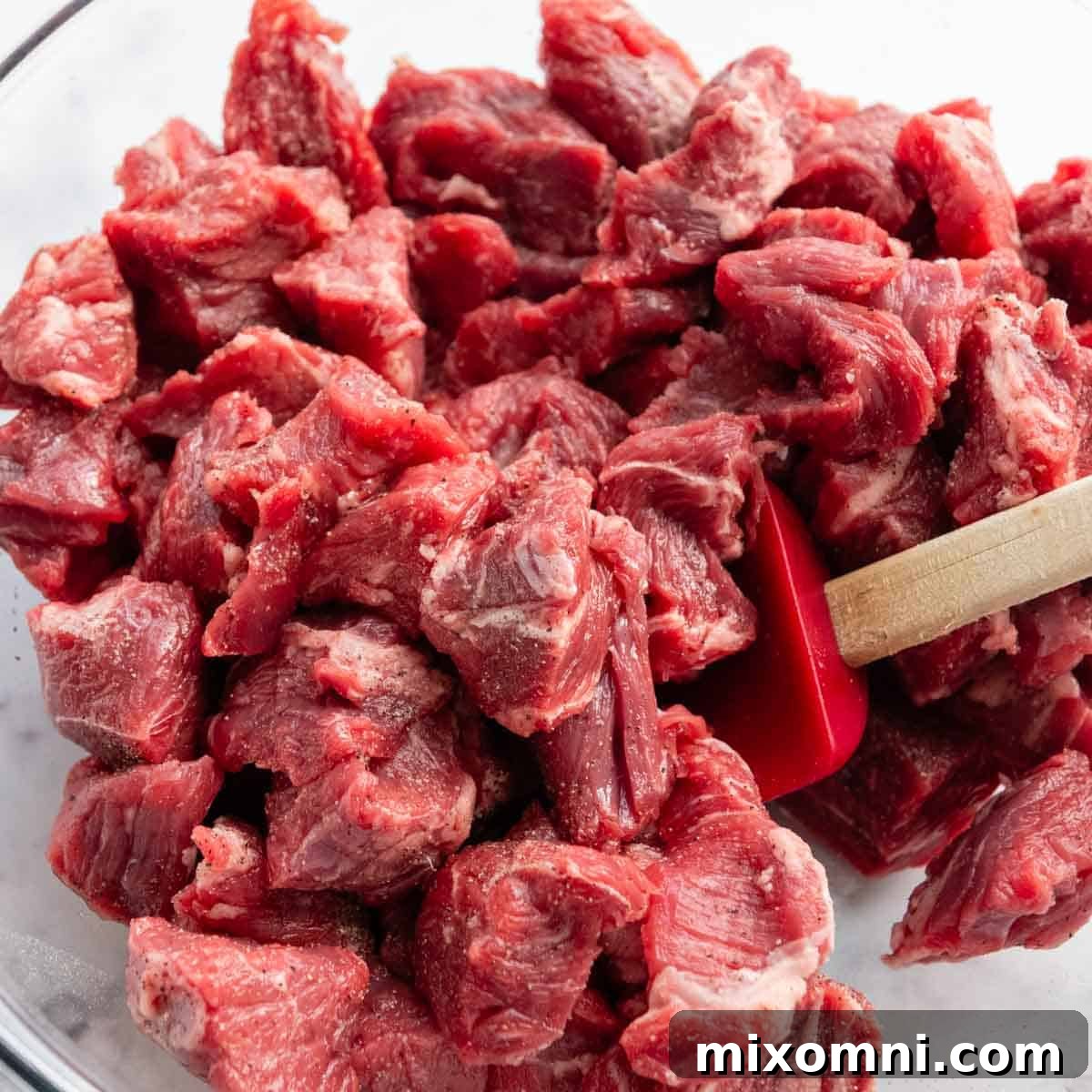 meat being stirred with salt and pepper in a bowl.
