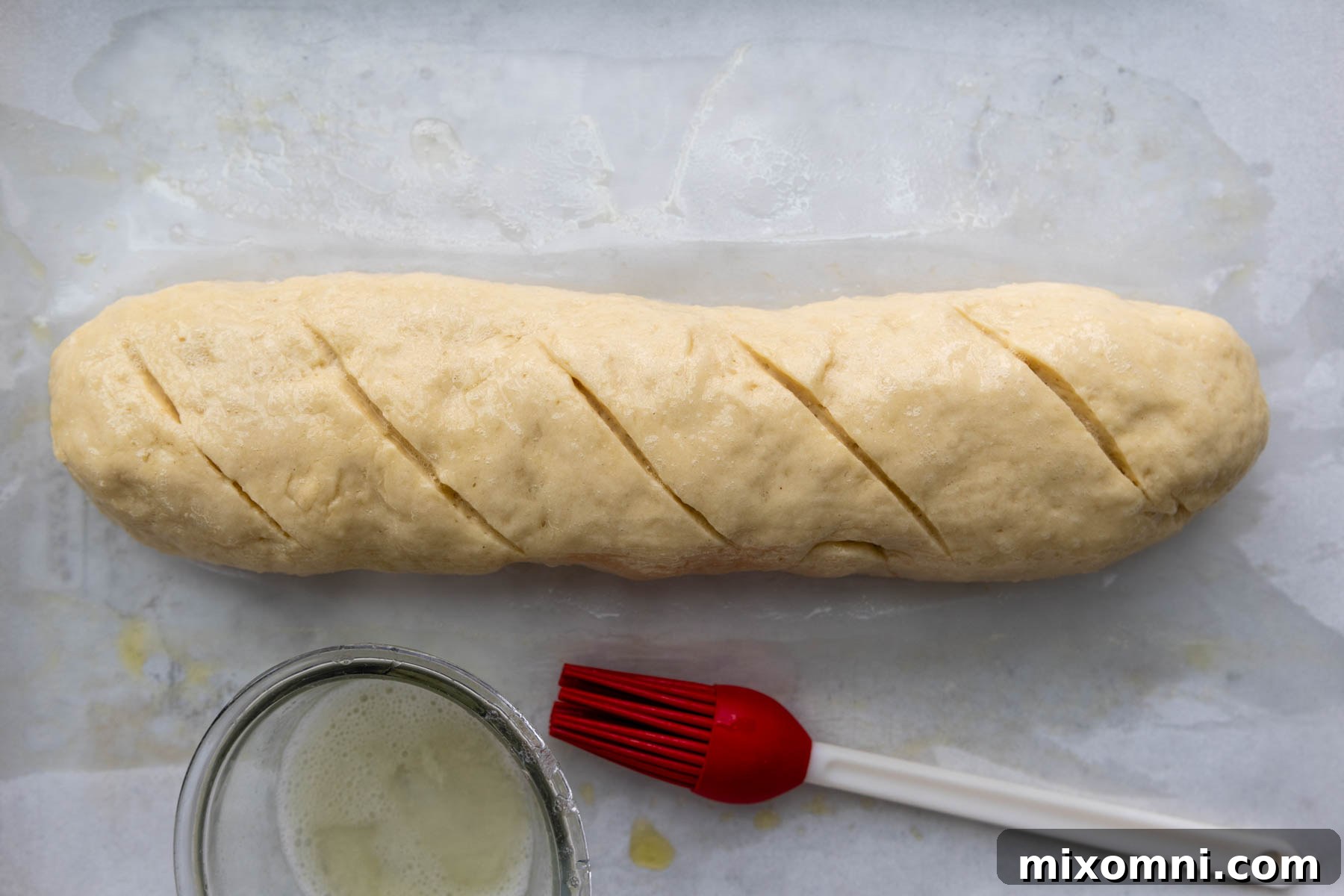 unbaked bread with egg white and pastry brush next to it.