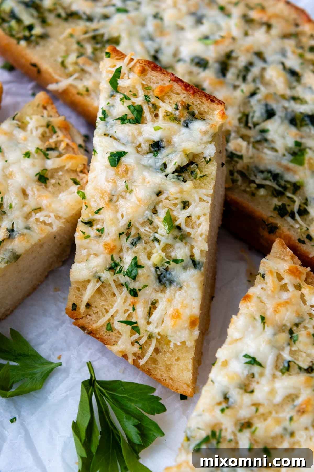 A perfectly sliced piece of gluten-free garlic bread resting on a stack of others, showcasing its crispy edge and soft texture.