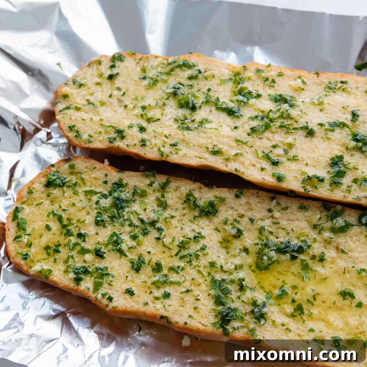 Garlic butter generously brushed over the two cut halves of a gluten-free bread loaf.