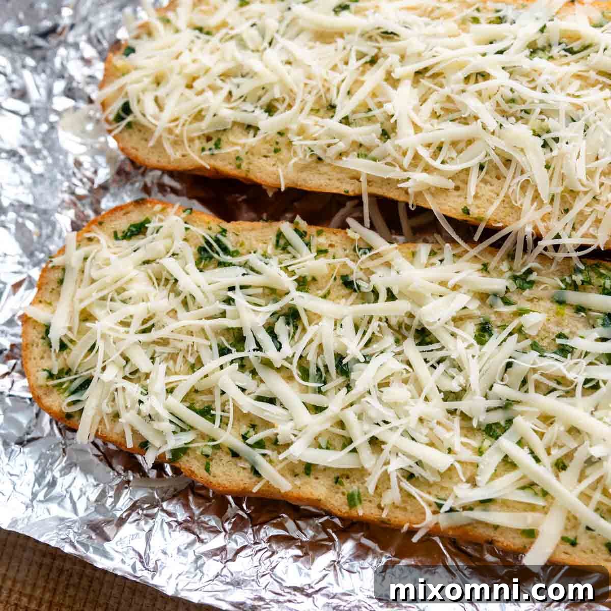 Prepared gluten-free bread halves, face up, with cheese sprinkled generously over them, ready for the oven.