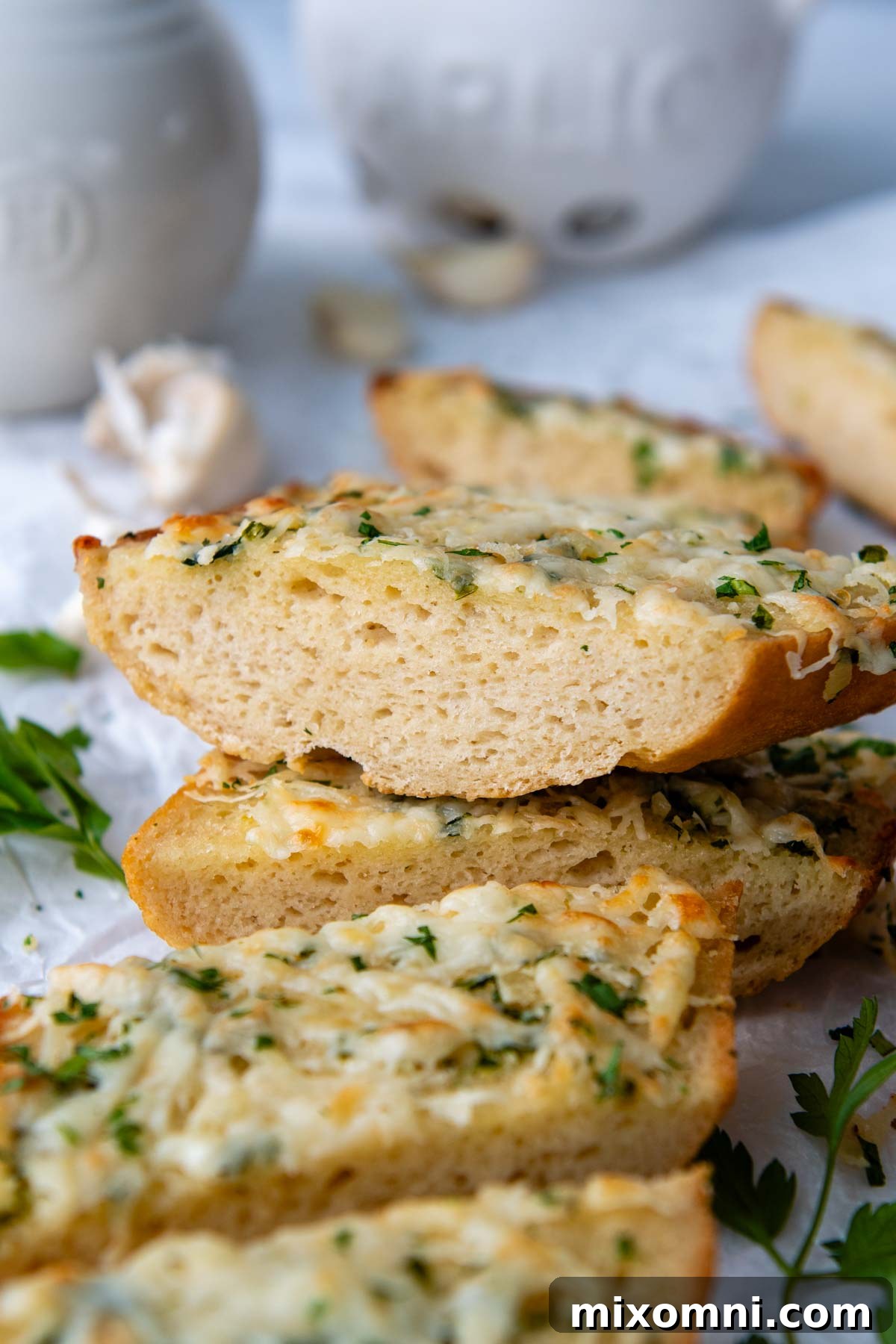A perfectly toasted, crispy slice of gluten-free garlic bread stacked atop other inviting slices.