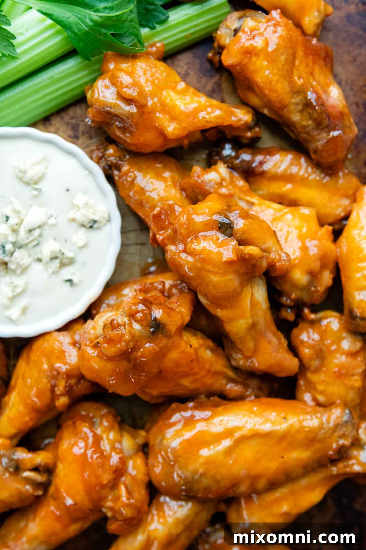 Overhead shot of perfectly baked chicken wings and drumettes arranged on a baking sheet, with a small bowl of dressing in the background.