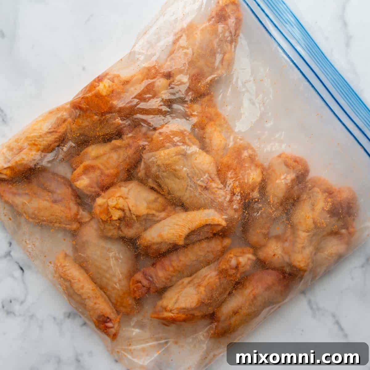 Unbaked wings in a ziplock bag, coated with seasoning, ready for baking.