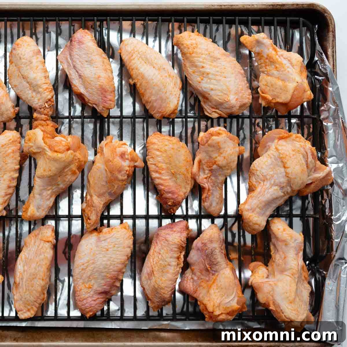 Crispy wings and drumettes arranged perfectly on a wire rack over a baking sheet.