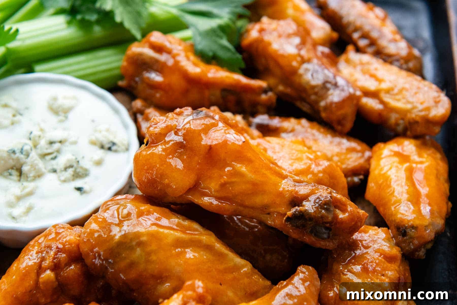 Buffalo wings served with a small bowl of blue cheese dressing and fresh celery sticks in the background.