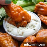 a buffalo drumette being dipped in blue cheese dressing.