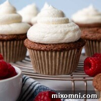 Chocolate almond flour cupcake on a cooling rack with raspberries scattered around.