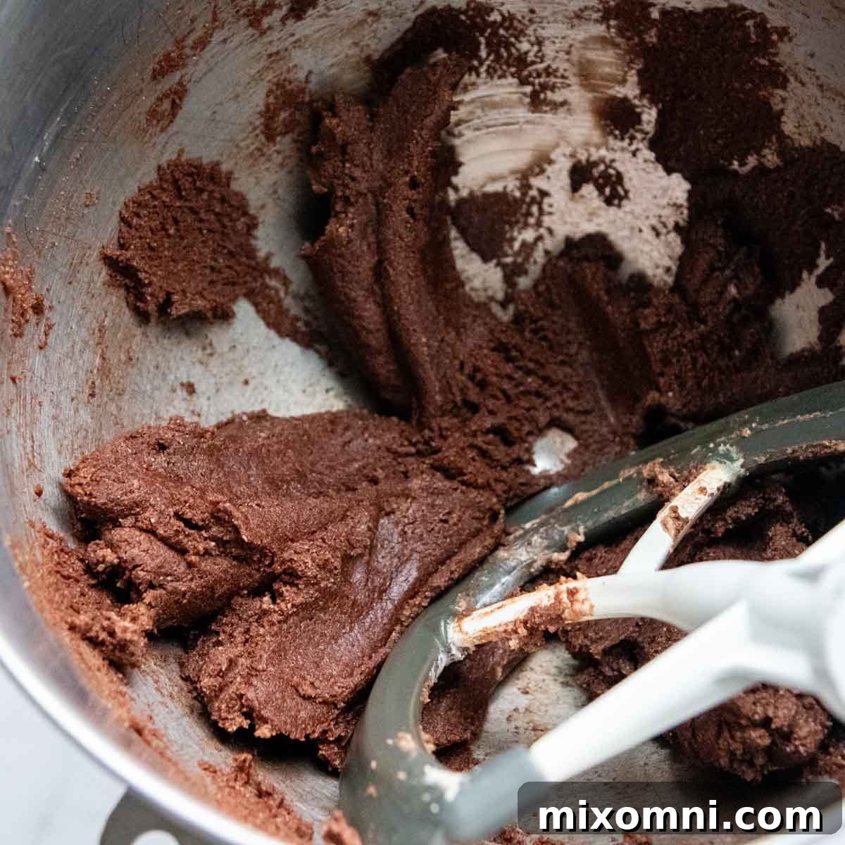 Thick chocolate almond flour mixture in a mixing bowl, resembling cookie dough.