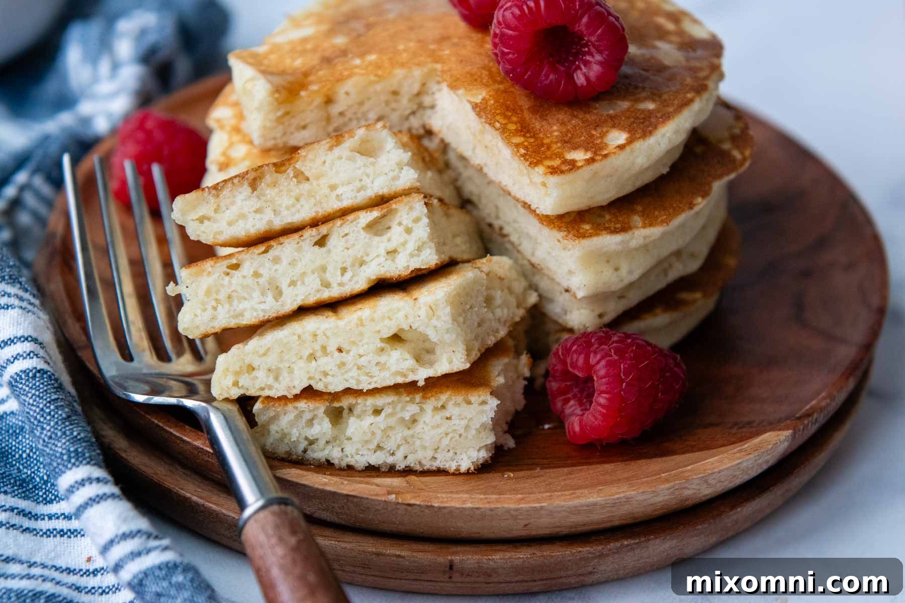 A close-up of a bite of gluten-free pancakes, showing their tender, fluffy interior, served on a rustic wooden plate.